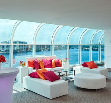 Lounging area with white couches, vibrant pillows & huge water view