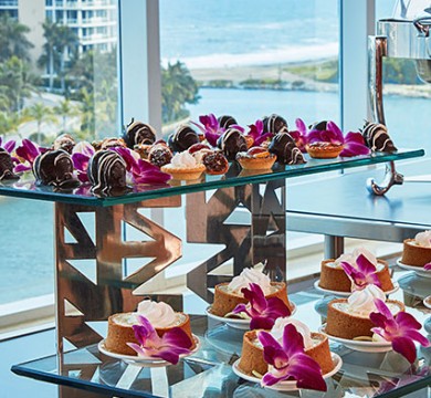 Wedding desserts served on glass tables with purple flowers