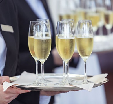 Waiter holding metal platter with champagne glasses