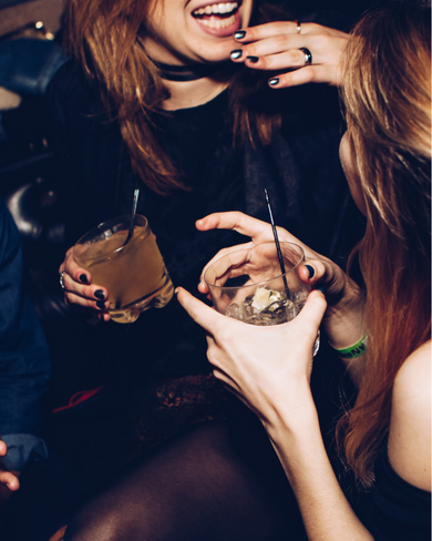 two women laughing and holding drinks