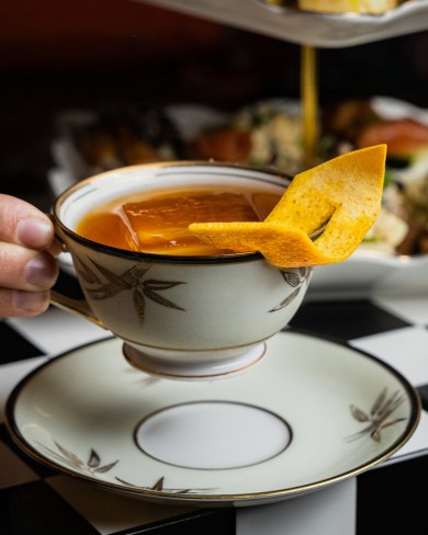 person holding a tea cup with an orange peel