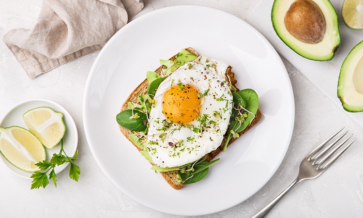 a plate of avocado toast with an over easy egg on top