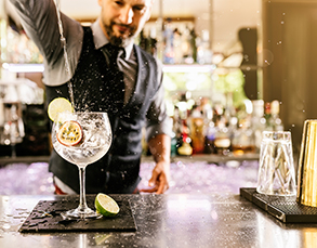 a bartender pouring a drink from a cocktail shaker into a cocktail class