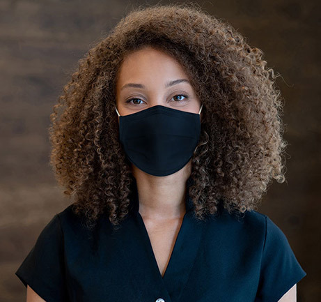 Woman with brown hair wearing face mask at front desk