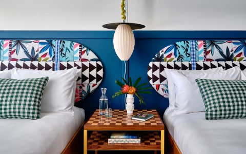 a blue wall with headboards with two beds and a night table in between them