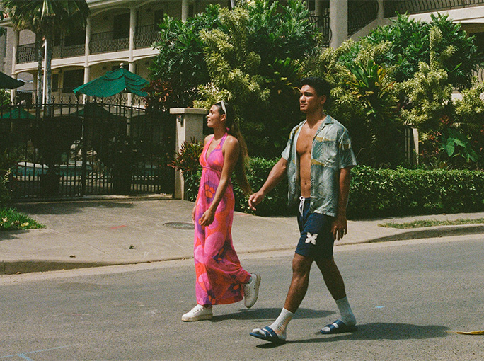 a woman with a pink dress walking by a mans side 