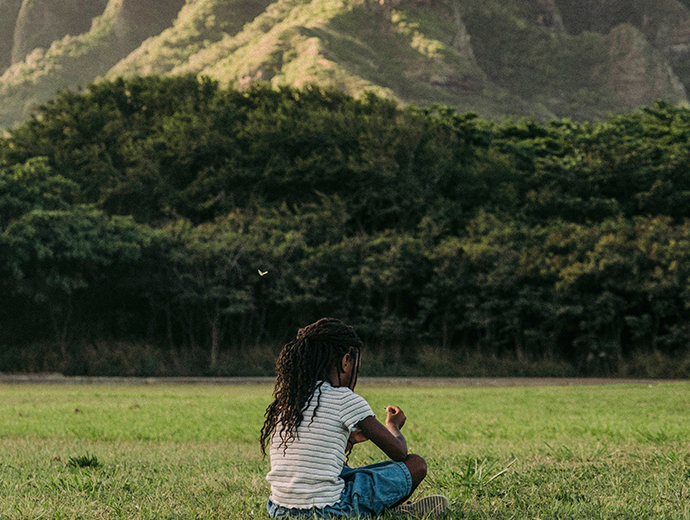 a small kid sitting by the mountains