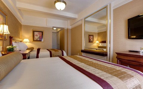 Double Queen beds in a large room with a mirror on the wall