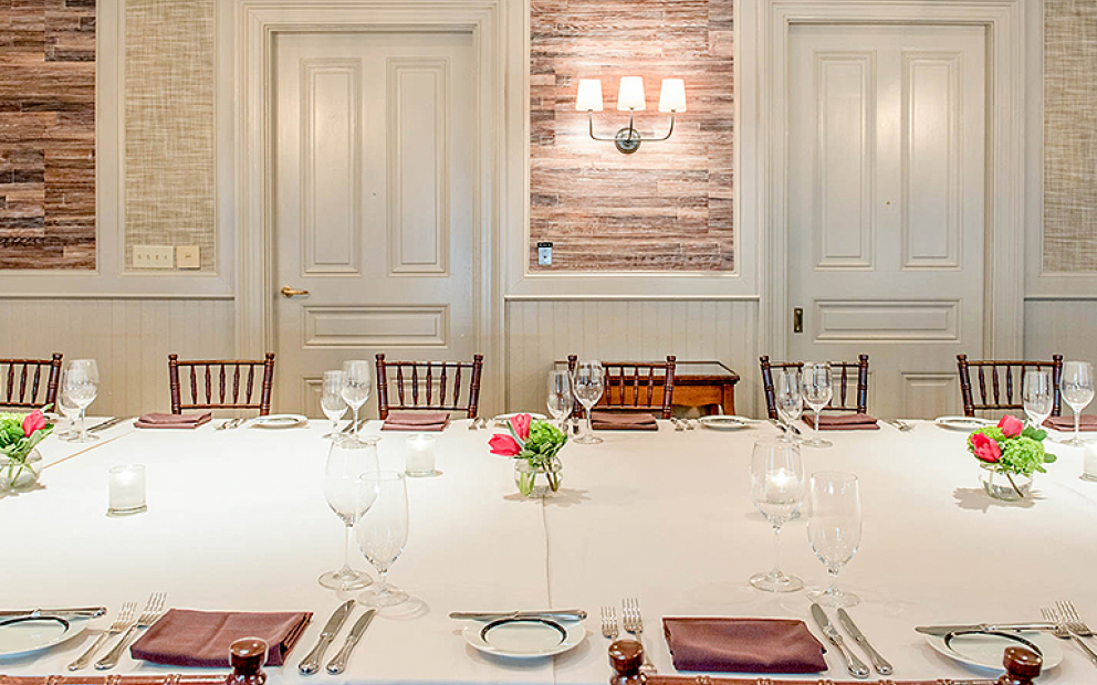Long rectangular table set for meal with white doors & wooden walls in the back