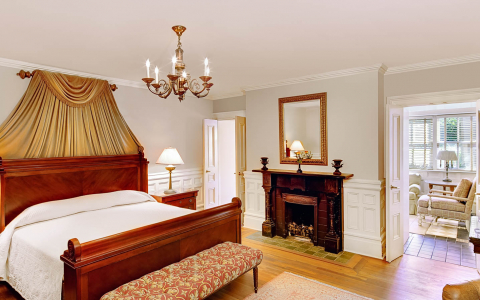 Room with king bed, wooden headboard, golden curtains & candlestick chandelier