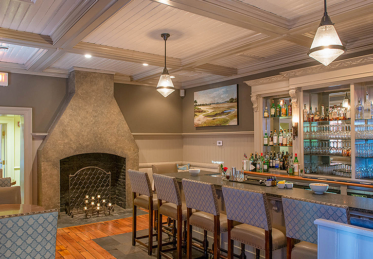 Dining space with fireplace next to blue stool bars in front of stocked bar with liquor bottles