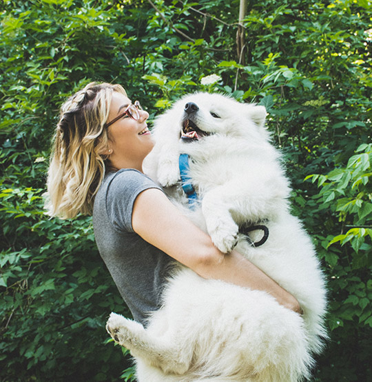 woman holding her white fluffy dog 