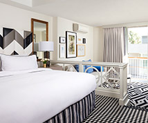 guest suite with white linens, black and white patterned accents, and a divider between the bed and living room area