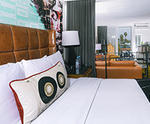 guest bedroom with white linens, decorative pillow, brown headboard, and view of the living room area behind a curtain