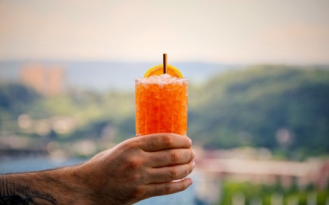 hand holding a tall glass with an orange cocktail