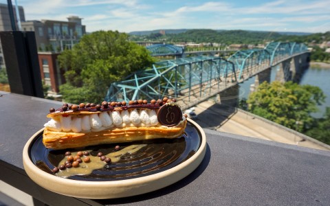 flakey pastry on a plate outside and a large bridge in the back