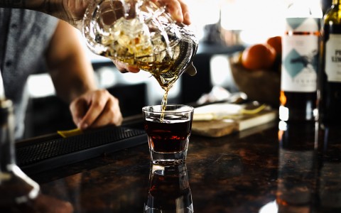 bartender serving a shaken drink into a small glass