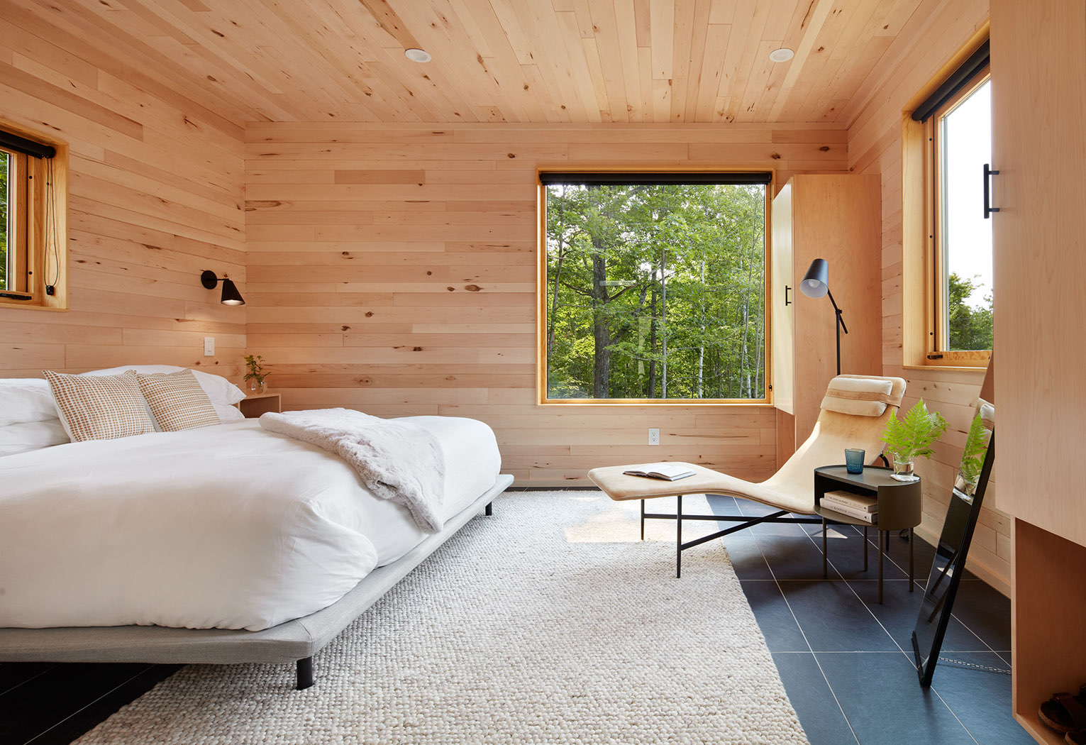 corner view of a treehouse bedroom with features as a queen bed and nightstands by the sides