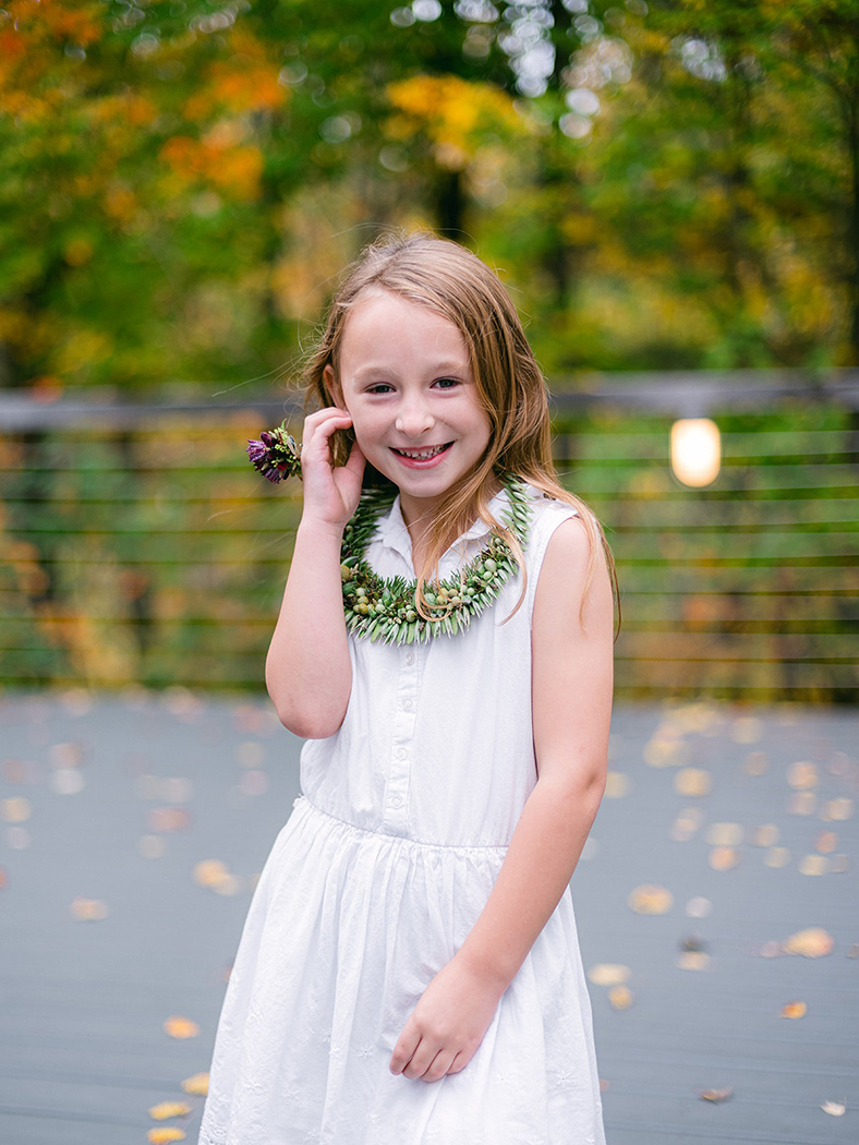 a little girl with a flower neckless  and ring  