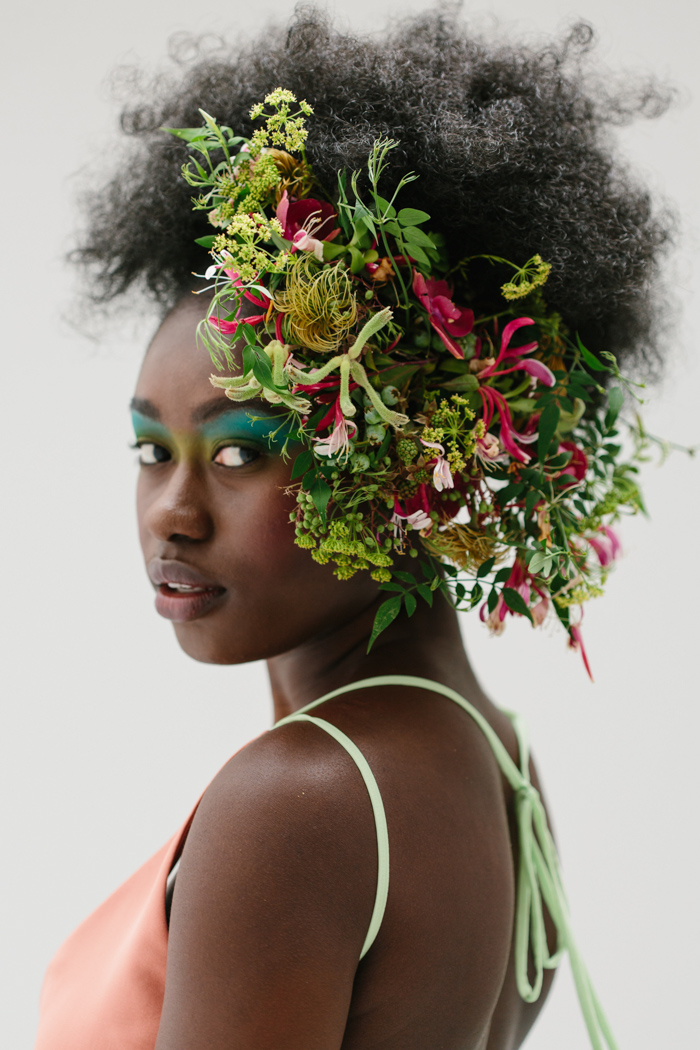 a lady with green leaves and flowers on her head 