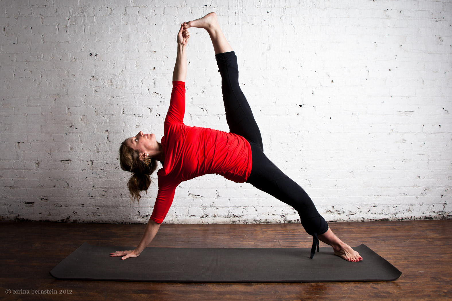 A woman wearing a red shirt doing a yoga pose