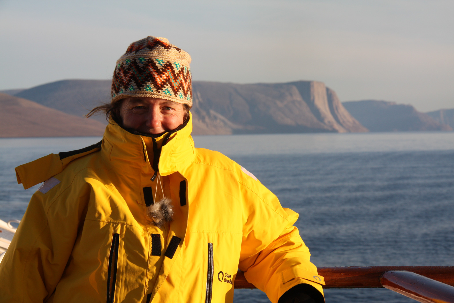 A happy woman wearing a yellow jacket on a cold landscape