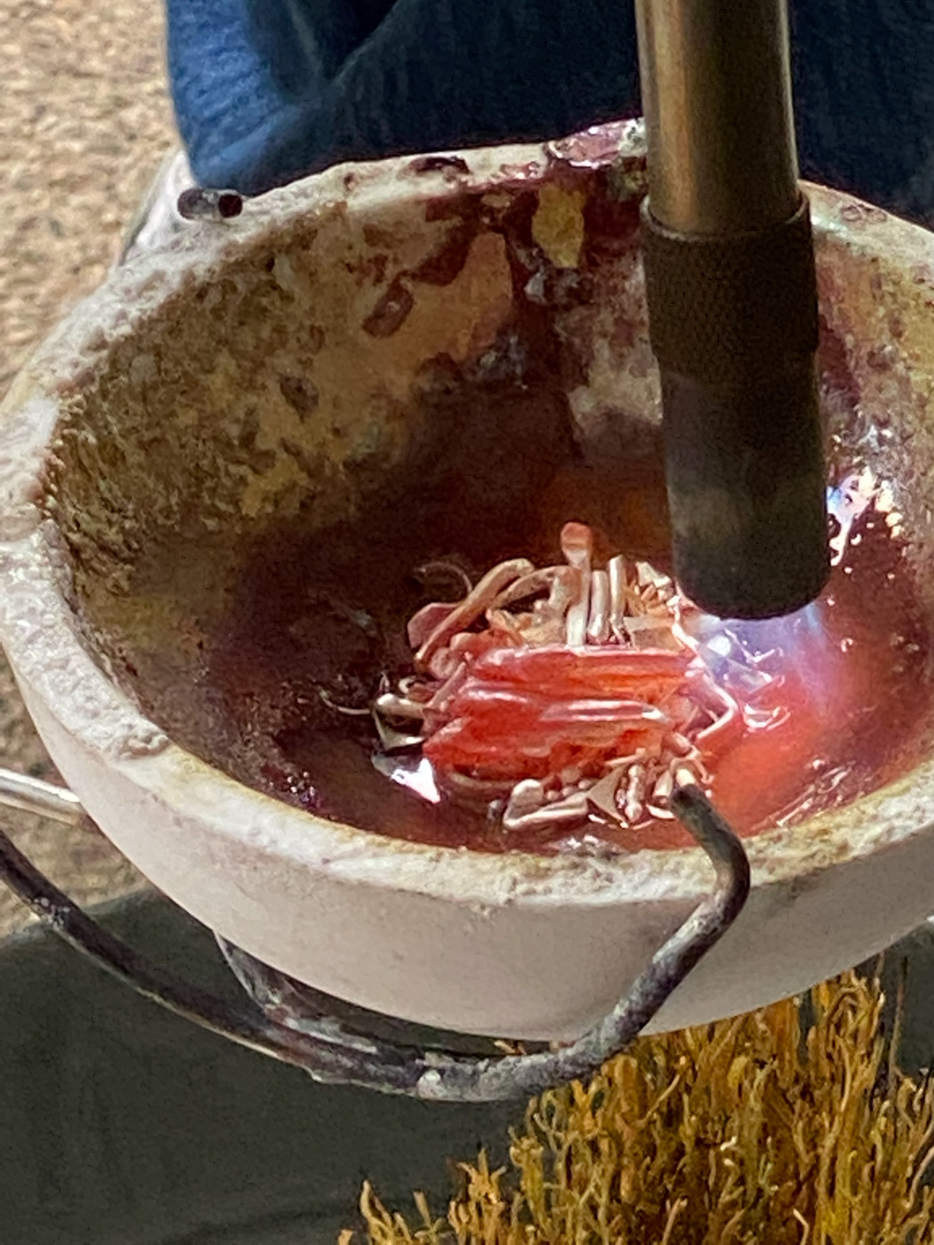 View of a  crock pot with some flowers and direct fire on them 