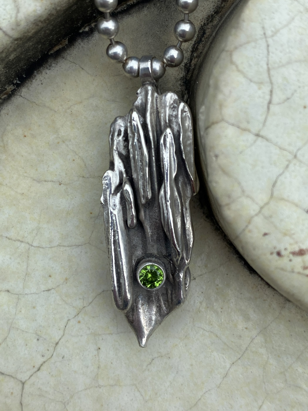 Closeup of a metal pendant with a green brilliant stone