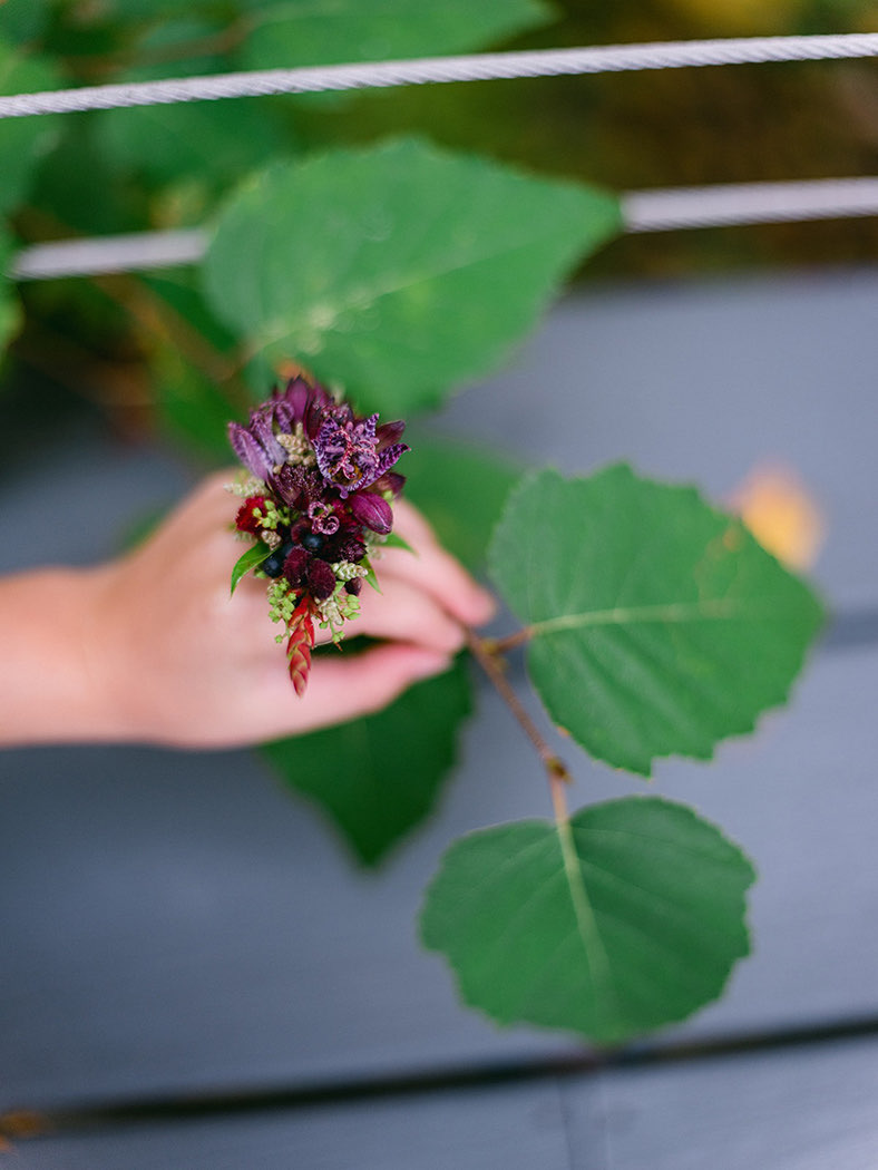 a hand holding a leave and flowers around finger