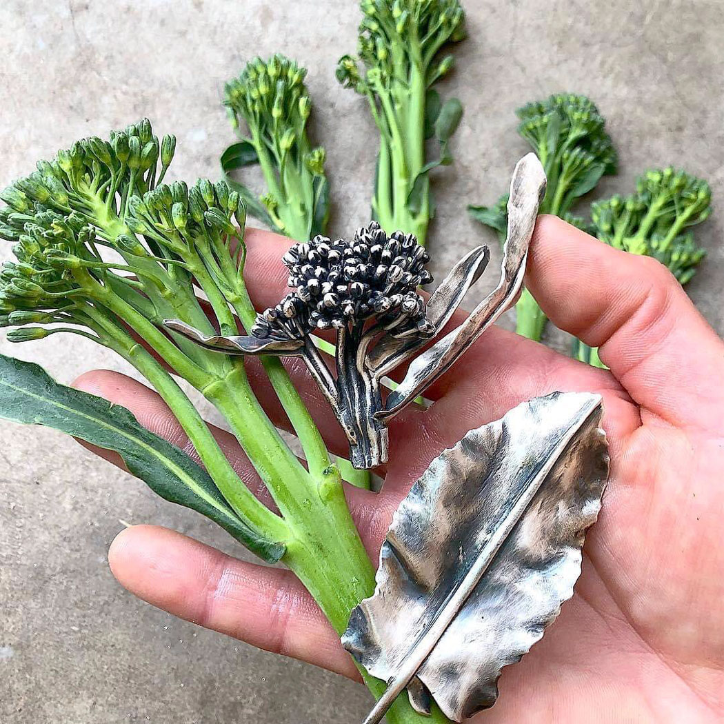 hand of someone carrying broccoli and tree branch