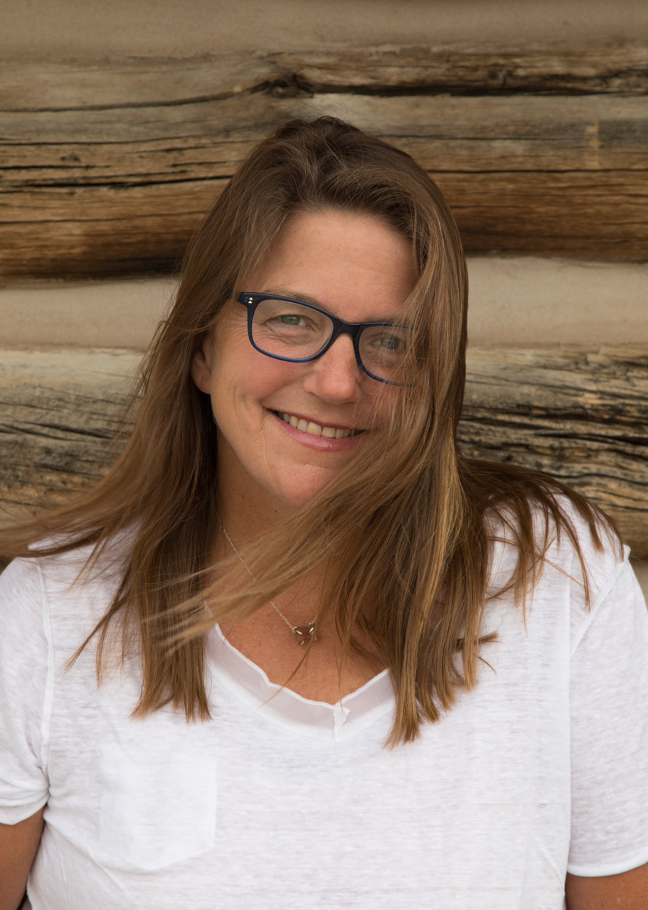 woman wearing black glasses is smiling and looking straight to the camera
