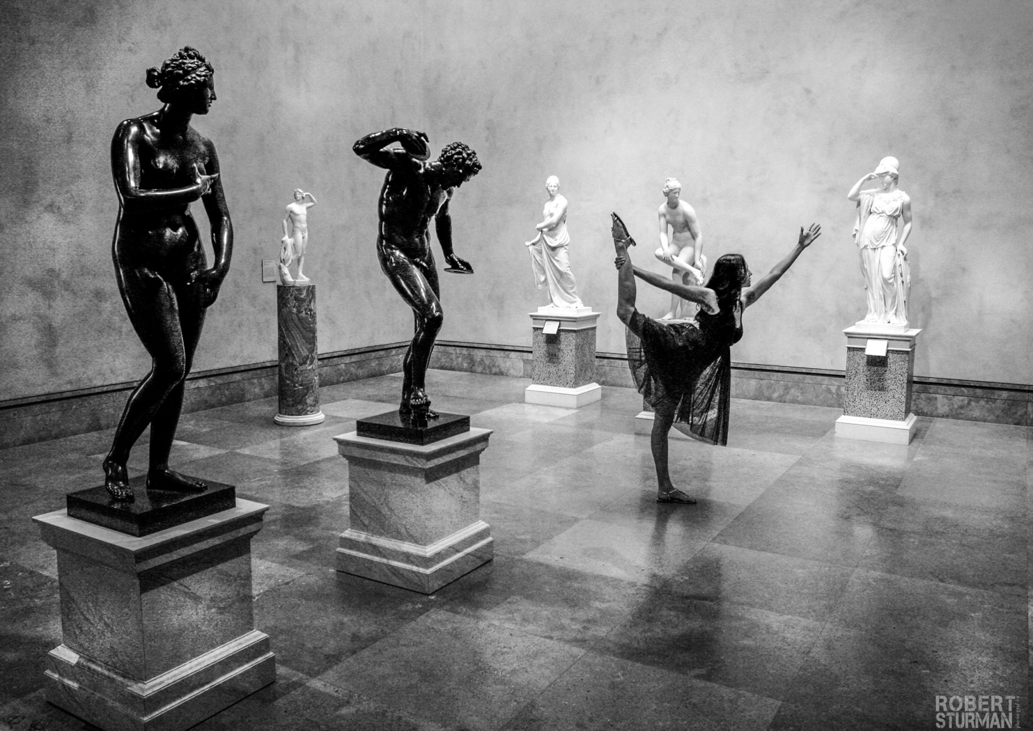 View of a ballet dancer in a room full of sculptures made in marble