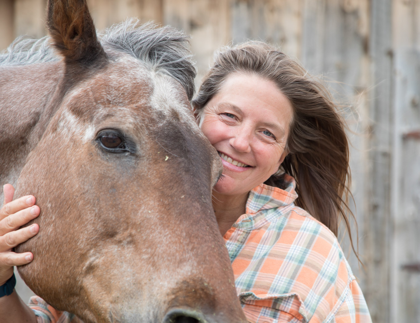 Portrait of a happy woman hugging a horse