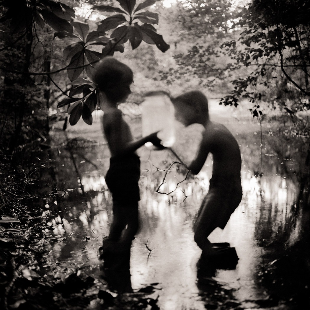 A black and white portrait of two children playing on a lake