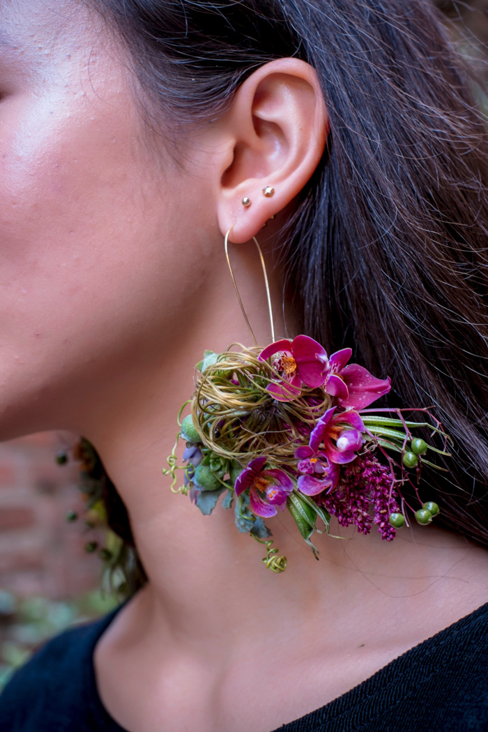 a lady wearing a large flower earring 