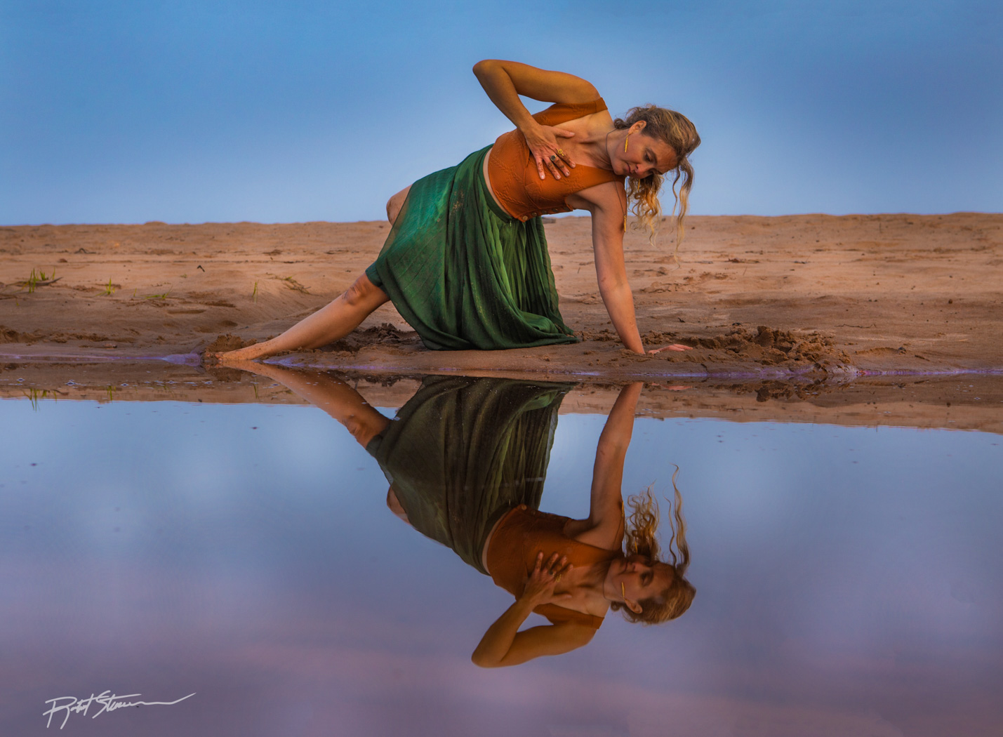 woman doing a yoga position near the water at sunset 