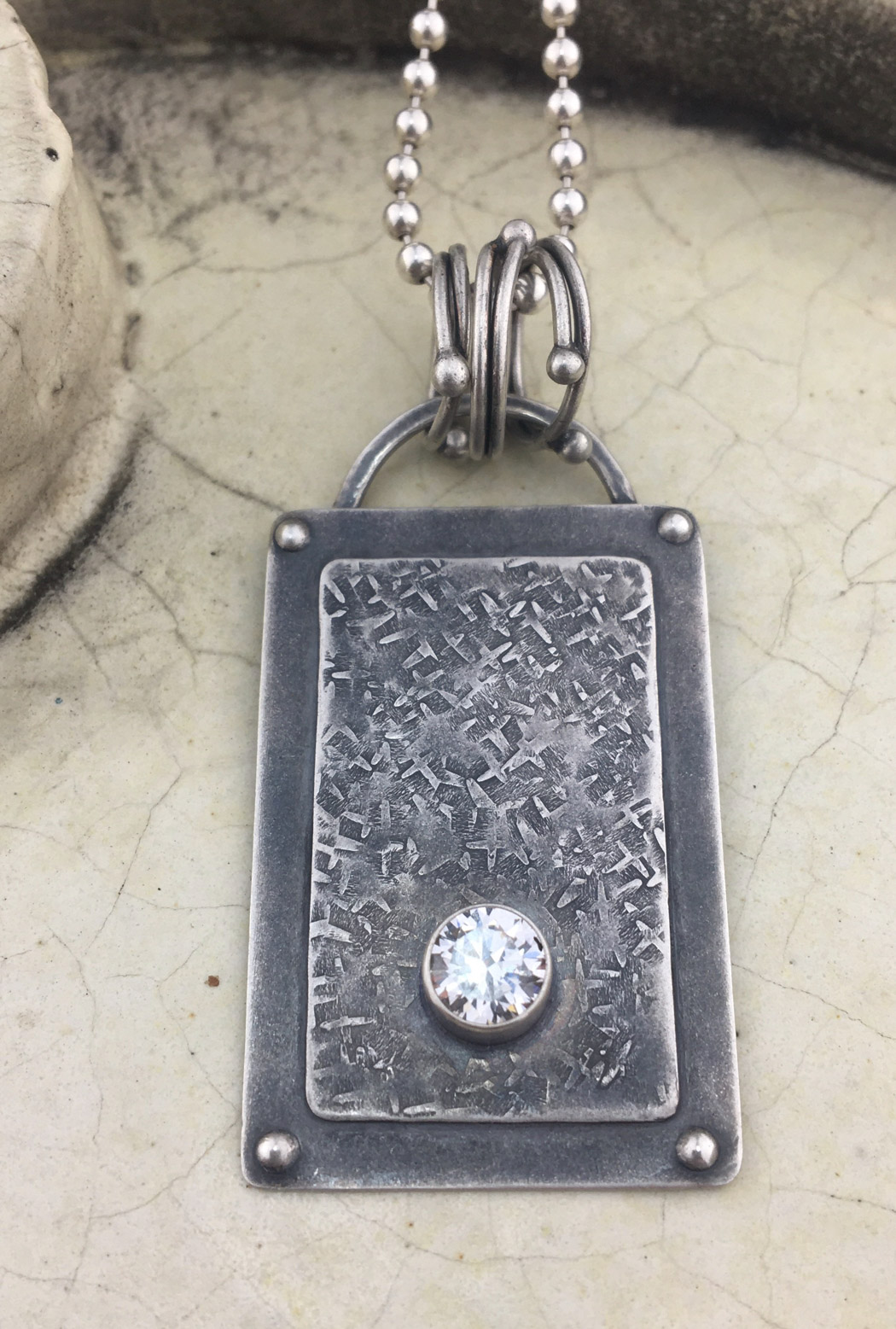 metal necklace with a square figure in the center 