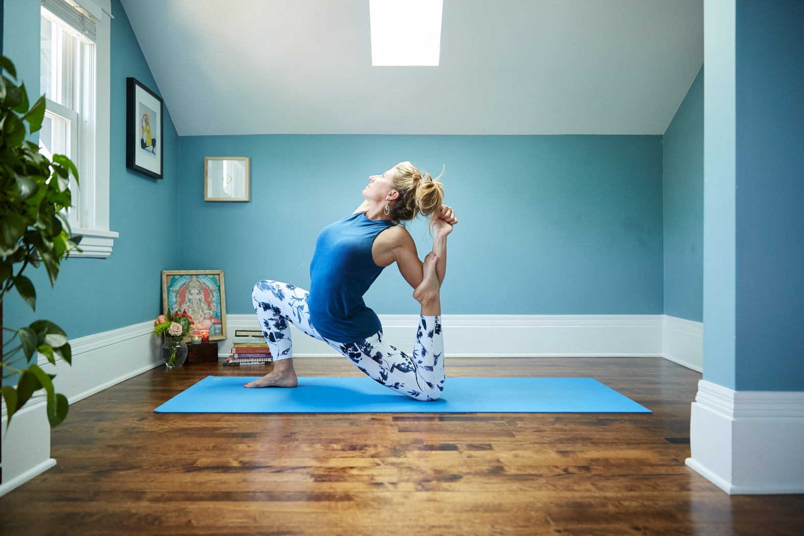 View of a woman doing a yoga pose on a blue room 