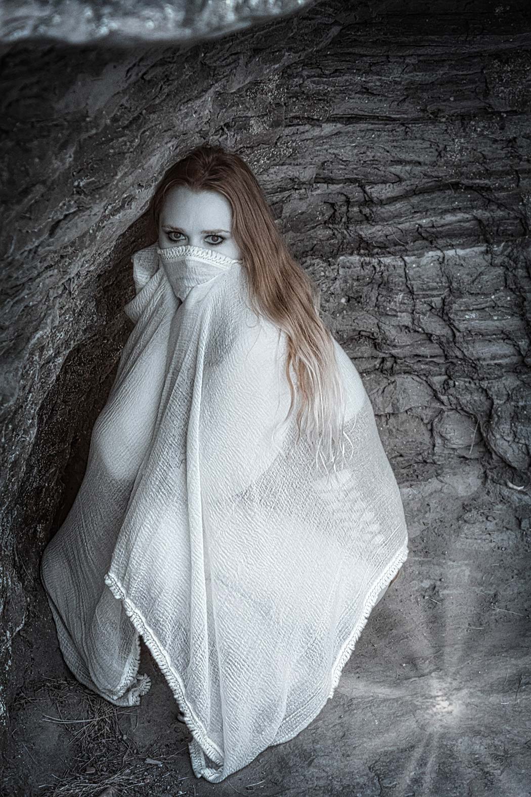 Portrait of a woman wearing a white blanket on a cave