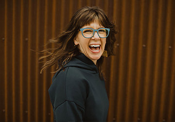 happy woman wearing blue glasses smiling and looking to the camera 
