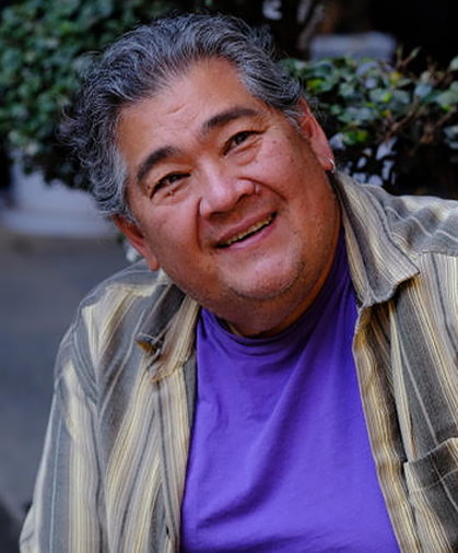 guy with a gray hair and wearing a purple shirt looking to the right side