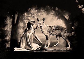 Sepia portrait of a little girl kissing an static wolf 