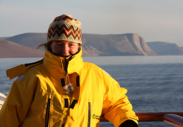 A happy woman wearing a yellow jacket on a cold landscape