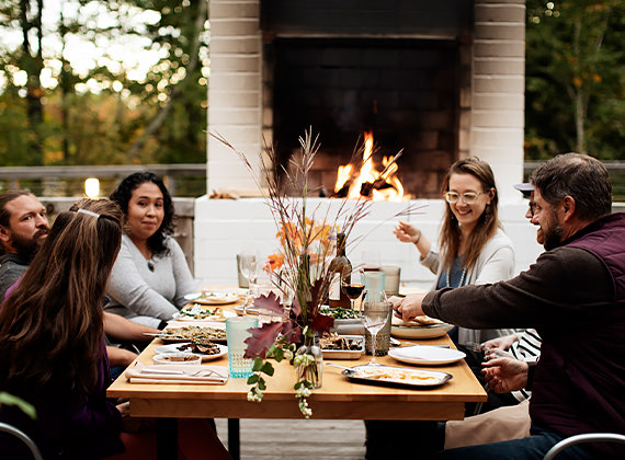 Friends enjoying a meal by an outdoor fireplace