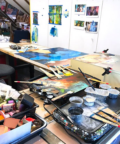 View of an artist studio, full of colorful paintings and brushes 