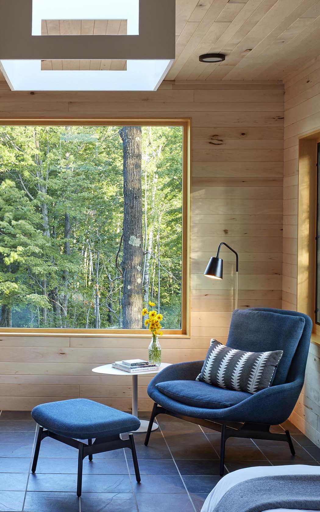 view of the corner of treehouse bedroom with features as a comfy blue armchair and a big window