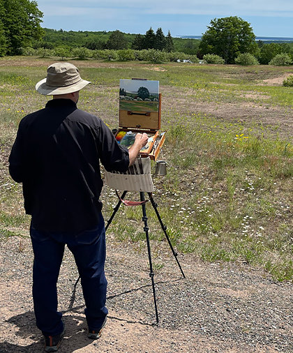 View of Joshua Cunningham, while painting a beautiful landscape outdoors