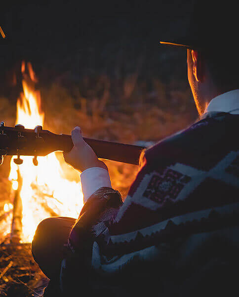 man with guitar around camp fire