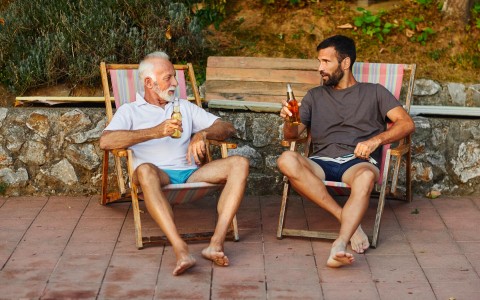 two men sitting on porch chairs chatting