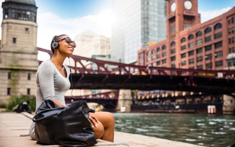 View of a young beautiful lady sitting next to the Chicago Lake